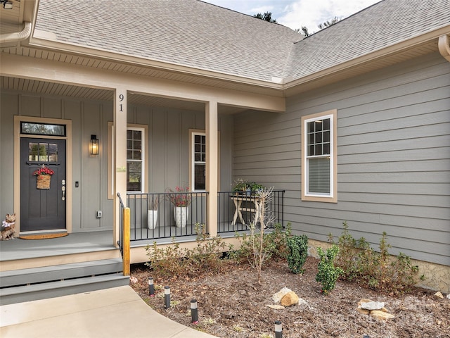 doorway to property with a porch and roof with shingles