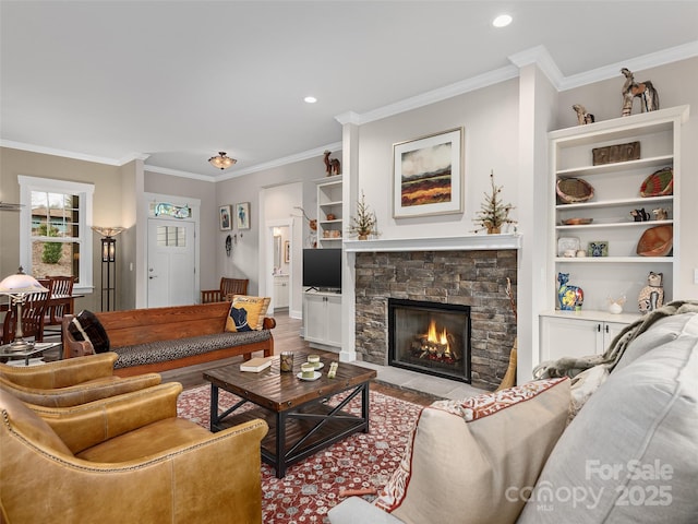 living room featuring ornamental molding, recessed lighting, a fireplace, and built in shelves