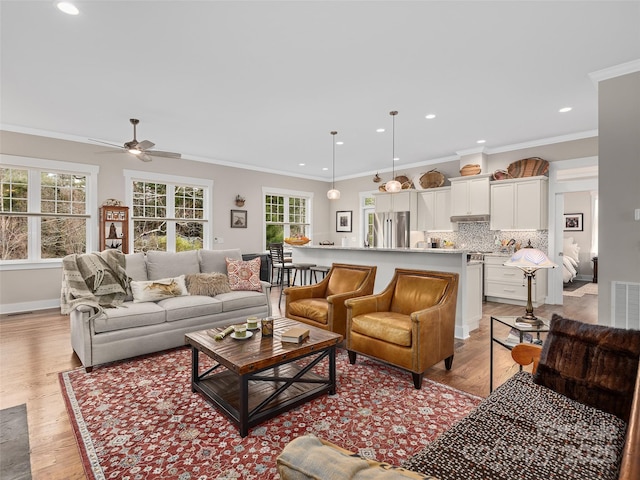 living room with crown molding, recessed lighting, visible vents, light wood-type flooring, and baseboards