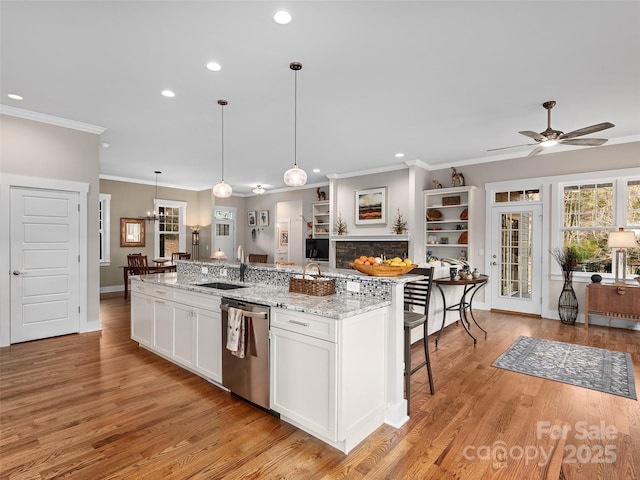 kitchen with white cabinetry, a sink, an island with sink, dishwasher, and a kitchen breakfast bar