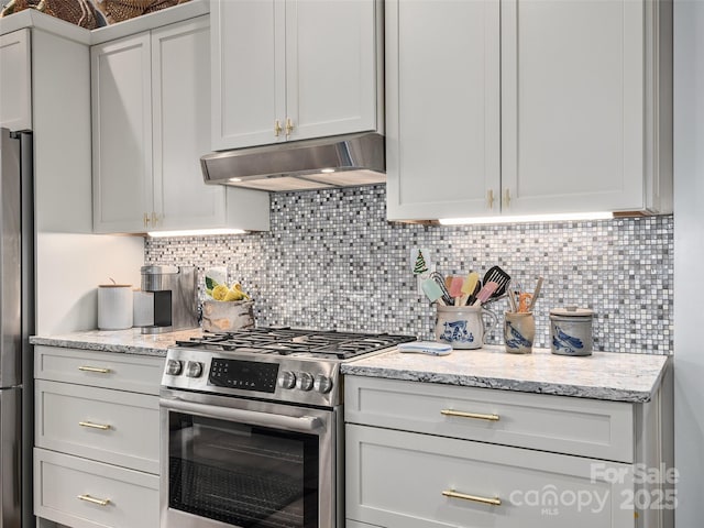 kitchen with under cabinet range hood, light stone counters, stainless steel appliances, and decorative backsplash