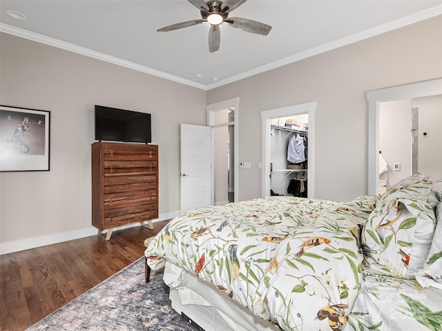 bedroom featuring baseboards, wood finished floors, a spacious closet, crown molding, and a closet