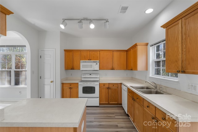 kitchen with white appliances, wood finished floors, visible vents, a sink, and light countertops