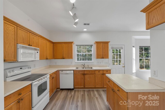 kitchen featuring visible vents, light wood-type flooring, light countertops, white appliances, and a sink