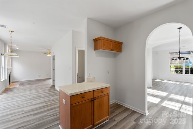 kitchen featuring open floor plan, light wood-style flooring, a fireplace, and brown cabinets