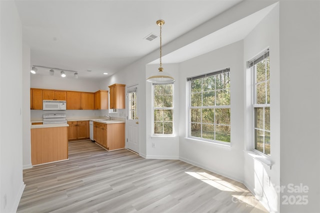 kitchen with white appliances, visible vents, light wood finished floors, hanging light fixtures, and light countertops