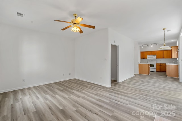 unfurnished living room with visible vents, baseboards, light wood-type flooring, a ceiling fan, and a sink