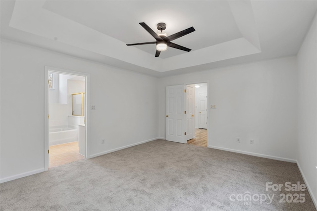 unfurnished bedroom featuring carpet flooring, a raised ceiling, and baseboards