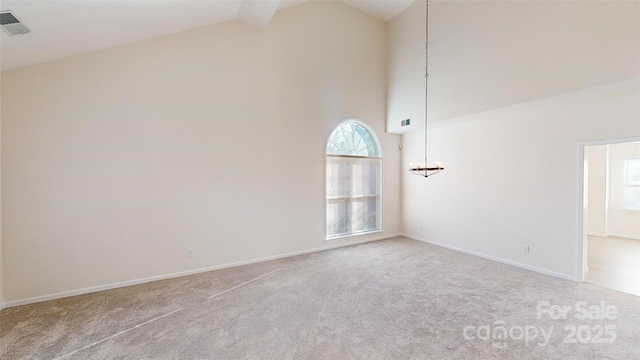 carpeted empty room with high vaulted ceiling