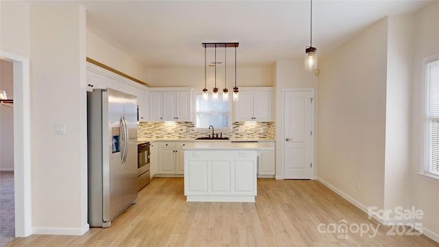 kitchen featuring stainless steel refrigerator with ice dispenser, range with electric cooktop, sink, decorative light fixtures, and a center island