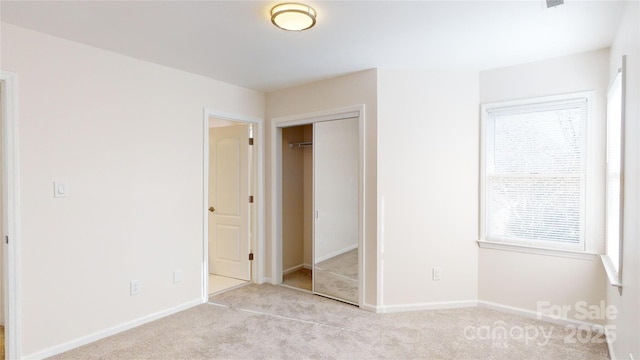 unfurnished bedroom featuring light carpet and a closet