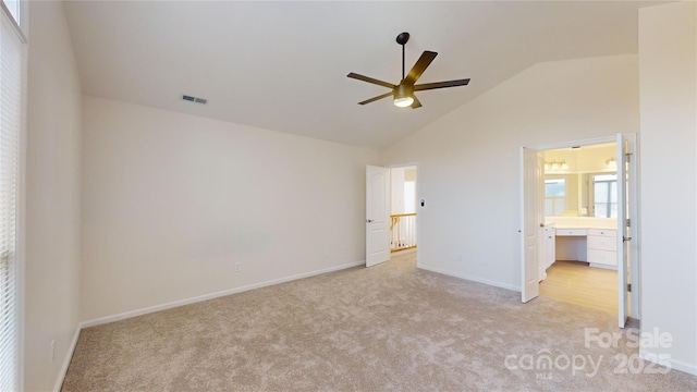 unfurnished bedroom featuring ceiling fan, high vaulted ceiling, ensuite bathroom, and light carpet