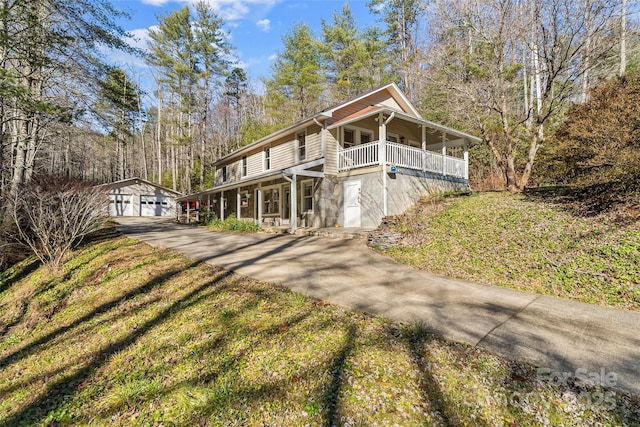 view of front of home with a porch, a garage, an outdoor structure, and a front yard