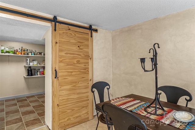 dining area featuring a barn door and a textured ceiling