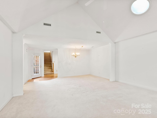 carpeted spare room featuring a chandelier and high vaulted ceiling