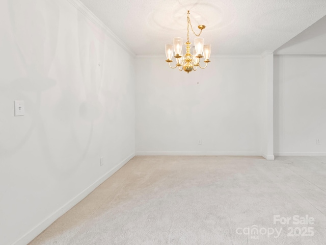 carpeted spare room with a notable chandelier, ornamental molding, and a textured ceiling