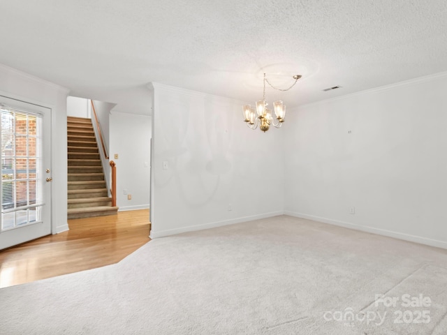 unfurnished room with ornamental molding, light colored carpet, a textured ceiling, and an inviting chandelier