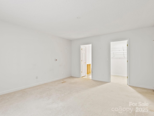 unfurnished bedroom featuring light colored carpet, a spacious closet, and a closet