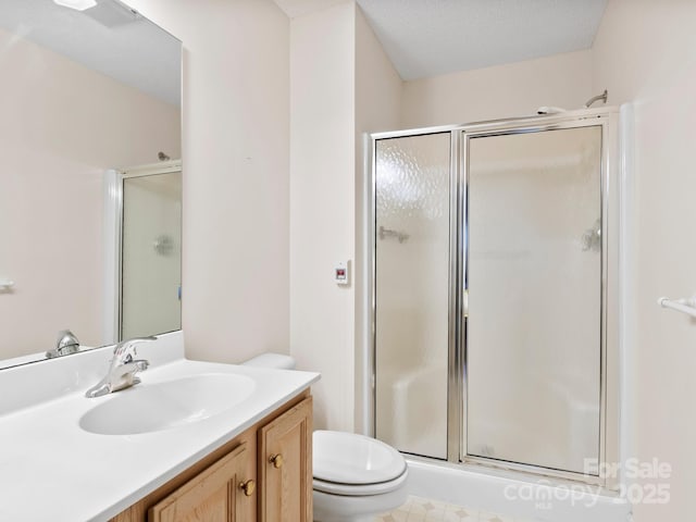 bathroom with a textured ceiling, vanity, toilet, and walk in shower