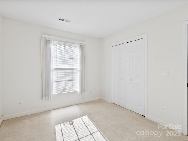 unfurnished bedroom featuring light carpet and a closet