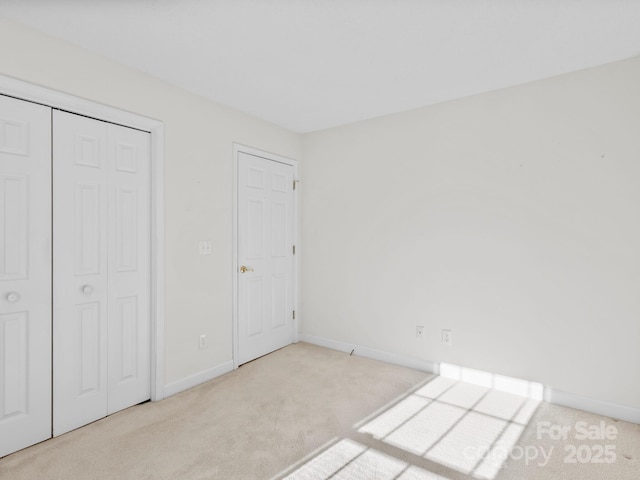 unfurnished bedroom featuring light carpet and a closet