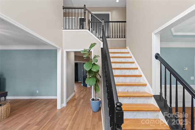 staircase featuring ornamental molding, hardwood / wood-style floors, and a high ceiling