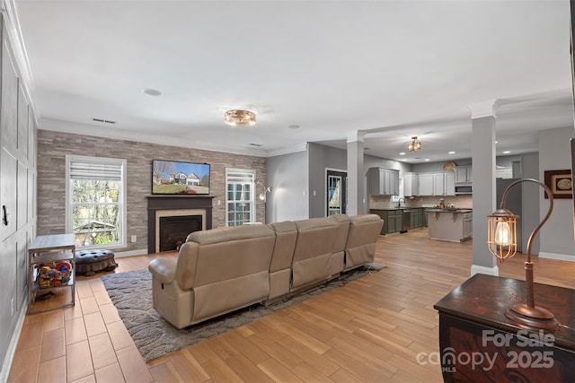 living room with sink, light hardwood / wood-style flooring, ornamental molding, and ornate columns