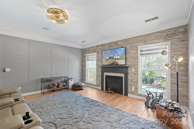 living room featuring ornamental molding, light wood-type flooring, and plenty of natural light