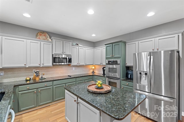 kitchen with stainless steel appliances, backsplash, and green cabinetry