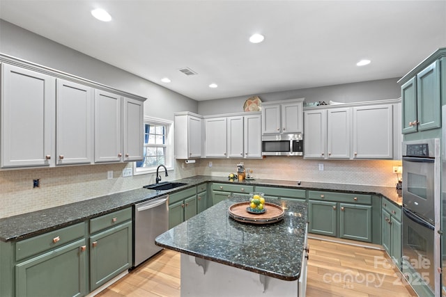 kitchen featuring stainless steel appliances, sink, backsplash, and light wood-type flooring