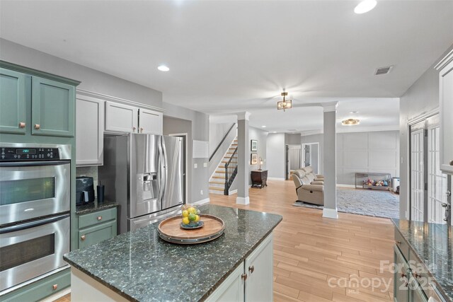 kitchen with white cabinetry, light wood-type flooring, ornate columns, and appliances with stainless steel finishes