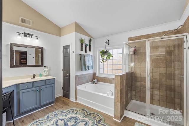 bathroom with vanity, hardwood / wood-style flooring, vaulted ceiling, and shower with separate bathtub