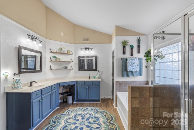 bathroom featuring a bath, vaulted ceiling, hardwood / wood-style floors, and vanity