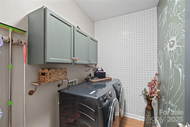 clothes washing area featuring cabinets, hardwood / wood-style floors, and washing machine and clothes dryer