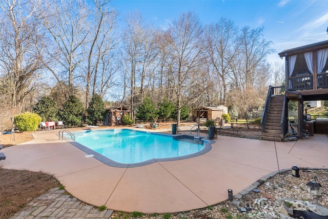 view of pool featuring a patio, a diving board, and a storage unit