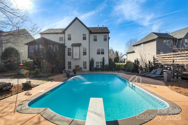 view of swimming pool featuring a diving board and a patio