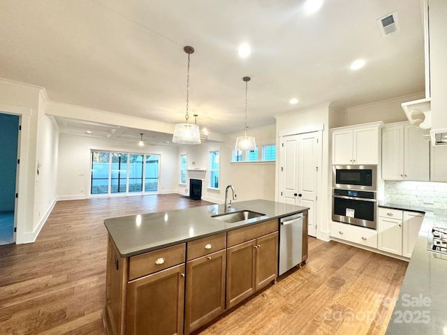 kitchen featuring sink, white cabinetry, a center island with sink, hardwood / wood-style flooring, and stainless steel appliances