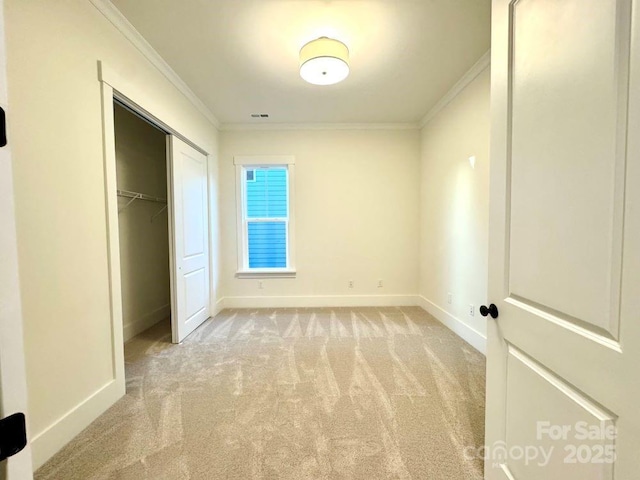 unfurnished bedroom featuring a closet, ornamental molding, and light carpet