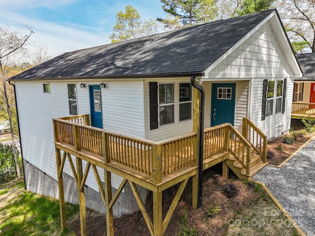 rear view of house with roof with shingles and a deck