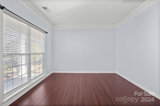 empty room with dark hardwood / wood-style flooring and crown molding