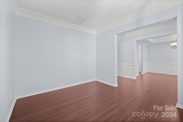 spare room with hardwood / wood-style flooring, crown molding, and a notable chandelier