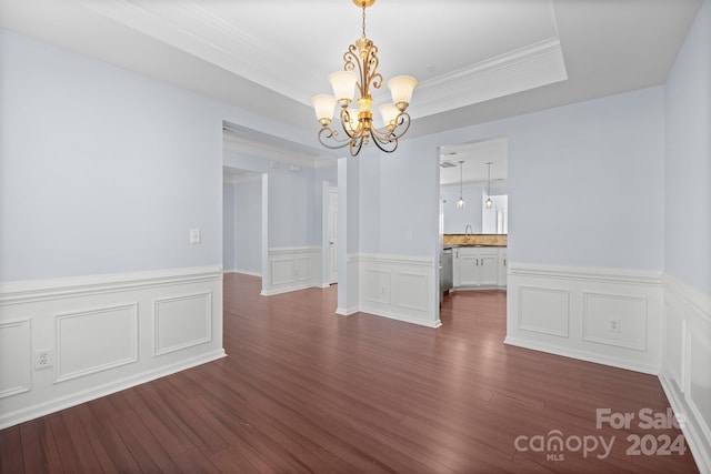 unfurnished dining area featuring a tray ceiling, dark wood-type flooring, sink, crown molding, and an inviting chandelier