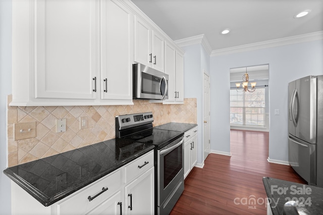 kitchen with appliances with stainless steel finishes, dark hardwood / wood-style flooring, ornamental molding, an inviting chandelier, and white cabinetry