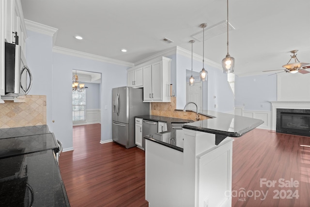 kitchen with sink, stainless steel appliances, tasteful backsplash, decorative light fixtures, and white cabinets