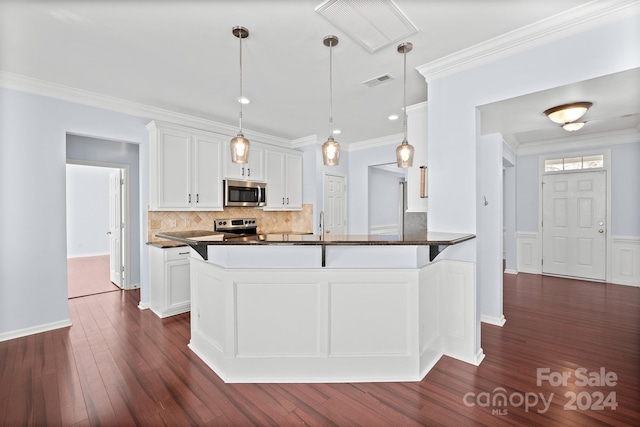 kitchen with white cabinetry, hanging light fixtures, dark wood-type flooring, stainless steel appliances, and crown molding