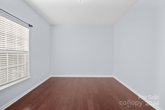 spare room with dark hardwood / wood-style flooring and a healthy amount of sunlight