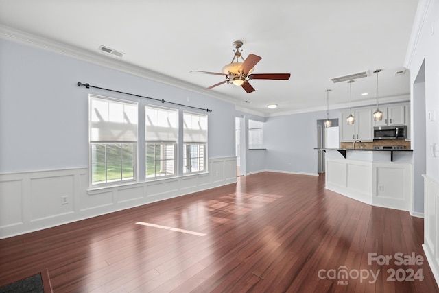 unfurnished living room featuring dark hardwood / wood-style floors, ceiling fan, and crown molding