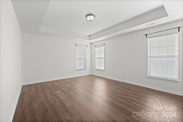 spare room with dark hardwood / wood-style floors and a raised ceiling