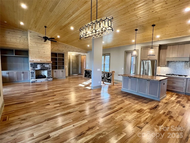 kitchen featuring hanging light fixtures, stainless steel refrigerator, a center island, and wood ceiling