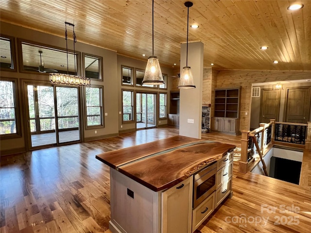 kitchen with pendant lighting, butcher block counters, a center island, wood ceiling, and light hardwood / wood-style floors